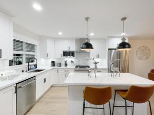 eine Küche mit weißen Schränken und eine große Insel mit Stühlen in der Unterkunft @ Marbella Lane – Contemporary Sophisticated Home in Sunnyvale + 29 Fotos