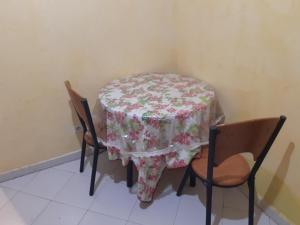 a table with a floral table cloth on it with two chairs at ma chambre in Casablanca +9 photos