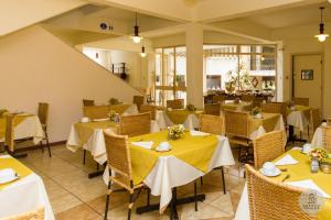 a restaurant with tables and chairs with yellow table cloth at Solara Hotel in São João del Rei