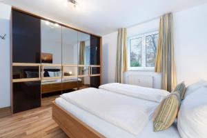- une chambre avec un grand lit blanc et un miroir dans l'établissement Wohnpark am Mühlenteich App 28 Sandkiste, à Timmendorfer Strand