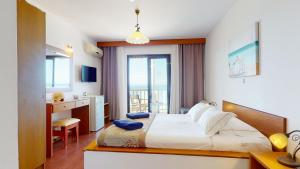 a bedroom with a bed and a desk and a kitchen at Acrotel Elea Beach in Elia