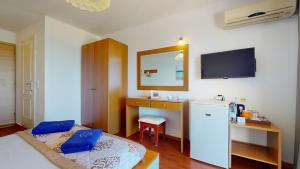 a room with a bed and a desk and a tv at Acrotel Elea Beach in Elia