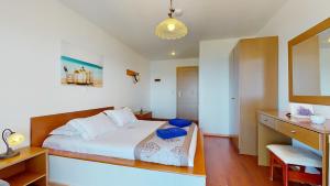 a bedroom with a bed and a desk with a chair at Acrotel Elea Beach in Elia