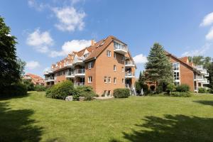 un grand bâtiment en briques dans une cour herbeuse dans l'établissement Wohnpark am Mühlenteich App 28 Sandkiste, à Timmendorfer Strand