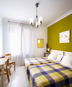 Habitación de hotel con 2 camas y mesa en Hostal Barrera, en Madrid