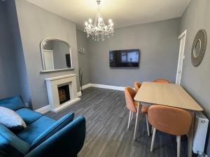 een woonkamer met een blauwe bank en een tafel bij Moda House Wigan - Beautiful 4 Bed Property in Pemberton
