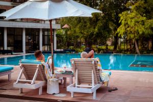 two people sitting in lawn chairs next to a pool at Buddha Maya Garden by KGH Group in Rummindei