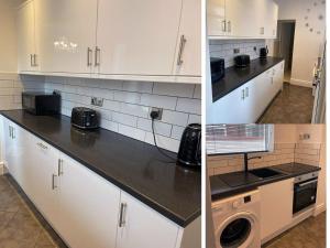 cocina con armarios blancos y encimera negra en Moda House Wigan - Beautiful 4 Bed Property en Pemberton