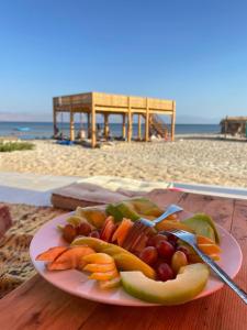 a plate of fruit and vegetables on a table near the beach at Yasmina Beach in Taba