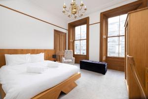 Un dormitorio con una gran cama blanca y una lámpara de araña. en ALTIDO 5 Bedroom Apt near Meadows and George Square en Edimburgo