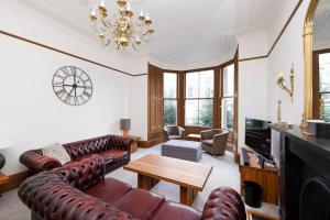 una sala de estar con muebles de cuero y una lámpara de araña. en ALTIDO 5 Bedroom Apt near Meadows and George Square en Edimburgo