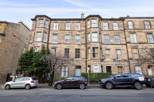 three cars parked in front of a large brick building at ALTIDO 5 Bedroom Apt near Meadows and George Square in Edinburgh