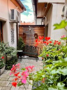 a patio with a bench and some red flowers at Lumiere House Sibiu in Sibiu