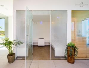 a glass shower in a room with two potted plants at AP Cabanas Beach & Nature - Adults Friendly in Cabanas de Tavira