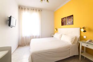1 dormitorio con cama blanca y pared amarilla en Hostal Barrera, en Madrid