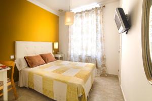 1 dormitorio con cama y pared amarilla en Hostal Barrera, en Madrid