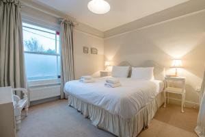 Schlafzimmer mit einem Bett mit weißer Bettwäsche und einem Fenster in der Unterkunft 18 Hartington, Aldeburgh in Aldeburgh
