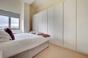1 dormitorio con 1 cama con armarios blancos y ventana en Crown Apartments 309 by Week2Week en Newcastle
