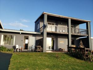 a large house with a balcony and tables and chairs at Mazeppa Sunrise Beach Accommodation in Mazeppa Bay