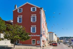 a red building on a city street with birds in the sky at Mare Mare Suites in Mali Lošinj