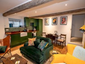 a living room with a green couch and a kitchen at A Hidden Gem in the Heart of Wells, Somerset in Wells