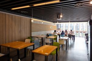 a restaurant with wooden tables and people sitting at tables at Chaiin Hotel - Dongmen in Taipei