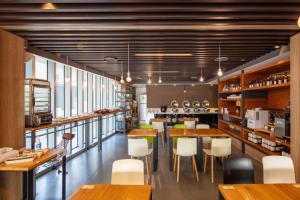 un restaurante con mesas de madera y sillas blancas en Chaiin Hotel - Dongmen en Taipéi
