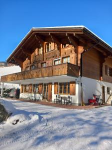un grand bâtiment en bois avec un balcon dans la neige dans l'établissement Chalet Pfyffer - Mountain view, à Grindelwald