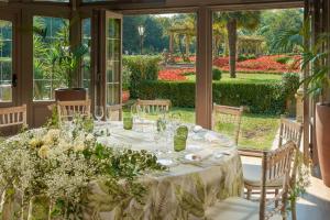 a table in the conservatory with a view of a garden at Palacio de Aviles Affiliated By Melia in Avilés