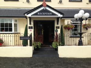 un bâtiment avec un panneau de réception devant une porte dans l'établissement The Belfray Country Inn, à Derry Londonderry