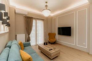 ein Wohnzimmer mit einem blauen Sofa und einem TV in der Unterkunft Satus Finem Egnatia's Luxury Apartment in Thessaloniki