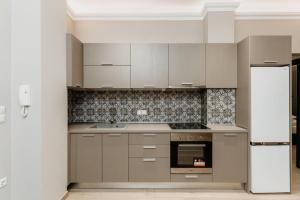 een keuken met grijze kasten en een fornuis met oven bij Satus Finem Egnatia's Luxury Apartment in Thessaloniki