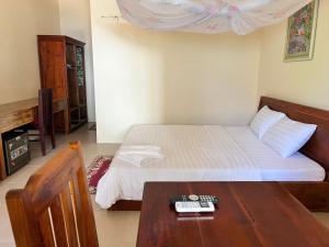 1 dormitorio con cama y mesa de madera en The Palm Tree Guesthouse, en Phu Quoc