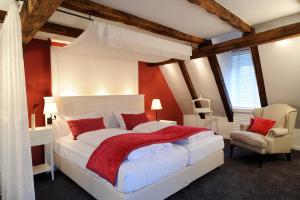 a bedroom with a white bed and a chair at Altes Amtshaus, 3-Sterne Hotel Garni Superior in Mulfingen-Ailringen