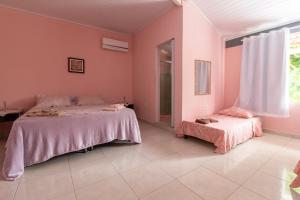 Schlafzimmer mit rosa Wänden und 2 Betten in der Unterkunft Suítes Valdira in Arraial d'Ajuda