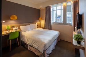 a hotel room with a bed and a desk and a window at Chaiin Hotel - Dongmen in Taipei