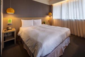 a bedroom with a large white bed and a window at Chaiin Hotel - Dongmen in Taipei