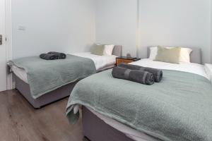 una camera con due letti con coperte di Taylor's Apartment Wimbledon a Londra