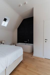 1 dormitorio con cama blanca y bañera en Duisbeke Logies, en Oudenaarde