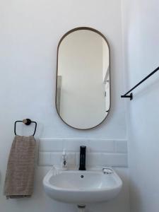 a bathroom with a white sink and a mirror at Beachside Studio Apartment on Surfers Corner in Cape Town
