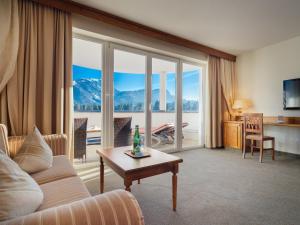 salon z kanapą i dużym oknem w obiekcie Hotel Alpina Wellness & Spa Resort w mieście Kössen