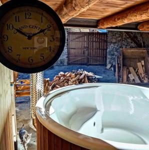 Antic Cal Pubill في Tornafort: ساعة معلقة على الجدار بجوار حوض الاستحمام