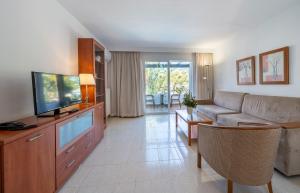 a living room with a couch and a tv at Apartamentos Los Tilos in Paguera