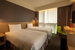 a hotel room with two beds and a desk and a window at Chaiin Hotel - Dongmen in Taipei