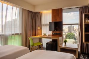 a hotel room with two beds and a desk with a television at Chaiin Hotel - Dongmen in Taipei