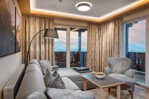 uma sala de estar com um sofá, cadeiras e janelas em Hotel Alpina Wellness & Spa Resort em Kössen