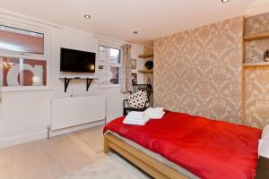 sypialnia z czerwonym łóżkiem i telewizorem z płaskim ekranem w obiekcie Whole house in Central Camden Town w Londynie