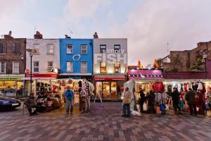 a group of people standing in front of a market at Whole house in Central Camden Town in London