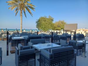 un patio con mesas, sillas y una palmera en Al Qurum Resort, en Mascate
