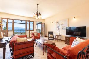 sala de estar con muebles de color naranja y TV de pantalla plana. en Villa Firefly by Villa Plus en Ágios Stéfanos